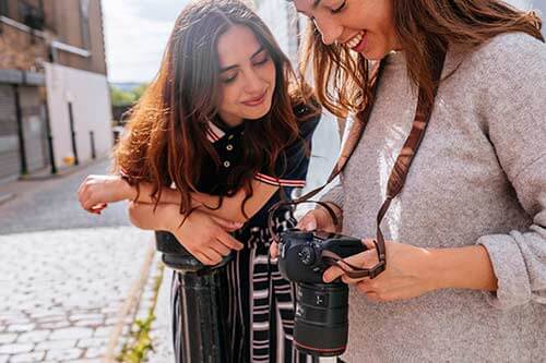 Zwei Fotografinnen schauen lächelnd auf das Display einer Canon Kamera