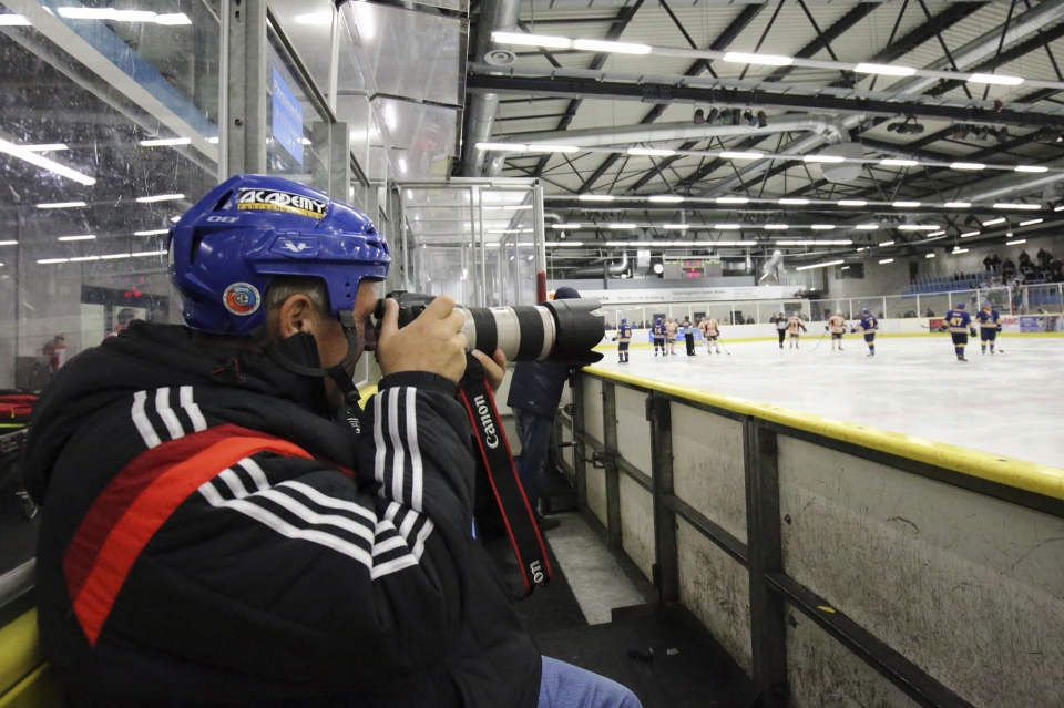 Mann fotografiert Eishockey mit Helm